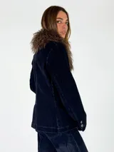 Chaqueta de denim azul oscuro con cuello de piel sintética desmontable, cierre frontal y puños con botones metálicos.