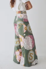 Pantalon de corte wide leg y tiro alto, confeccionado en tela con estampado deportivo que incluye pelotas de futbol y raquetas de tenis en tonos verde, rosa y beige.