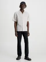 Pantalón chino de sarga elástica, color negro, de corte slim y talle medio. Incluye cinturón con hebilla en forma de D.