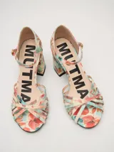 Sandalias de tacón cuadrado de 8 cm, confeccionadas en charol color crema. Presentan un diseño de tiras finas entrelazadas en la parte frontal y una correa ajustable con hebilla metálica en el tobillo.