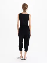Pantalon negro de corte tipo babucha, con cintura estructurada, presillas para cinturón, bolsillos traseros y ruedos ajustados con puños tejidos.