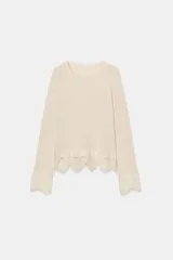 Top de tejido rústico color beige con cuello redondo y mangas largas, con aplicación de crochet a tono en los puños y el ruedo.