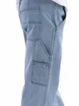 Pantalón jean celeste de corte amplio, estilo carpintero, con bolsillos laterales y traseros.