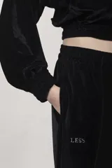 Pantalón de terciopelo negro, corte medio, cintura elástica, bolsillos laterales, logo bordado y costuras delanteras.