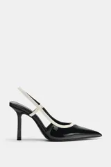 Zapatos de tacón alto fino y destalonados, con acabado efecto acharolado en color negro y detalles en blanco combinados en las tiras y el borde. Presentan puntera fina.