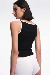 Musculosa tipo rib blanca con escote bote, corte al cuerpo y ribetes en contraste de color negro.