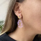 Aros colgantes con base circular rosa, detalle de strass y dije transparente con diseño abstracto celeste.