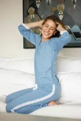 Pijama de algodón celeste con terminaciones de puntilla blanca en ruedo de remera y laterales de pantalón. Remera de manga larga y pantalón recto con elástico en la cintura y lazo.