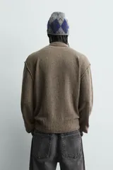 Polo de punto con cuello solapa y cierre frontal de tres botones. Presenta un diseño de manga larga con acabado en rib en puños y cintura, en un tono marrón jaspeado.