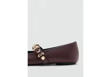 Zapato chatita de cuero sintético color marrón, con punta cuadrada, cordones decorativos en la capellada y una tira en el empeine adornada con tachas y argollas doradas.