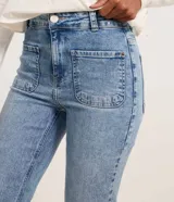 Pantalón boot cut de tiro alto confeccionado en denim celeste, con bolsillos delanteros y traseros, trabillas en la cintura y terminación deshilachada.