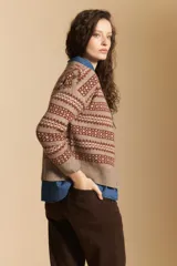 Cardigan corto de tejido jacquard con diseño geométrico en tonos beige y crema, con cierre frontal de botones y cuello redondo.