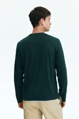Remera de manga larga color verde oscuro, con cuello redondo ribeteado y corte estándar.