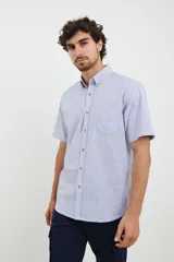 Camisa de manga corta a rayas verticales azules y blancas, con cuello abotonado y bolsillo en el pecho.