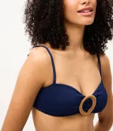 Top de bikini bandeau azul marino confeccionado en microfibra texturizada, con tirantes finos regulables y removibles. Cuenta con un aplique redondo de paja en el centro del busto y copas extraíbles.