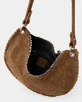 Bolso de mano tipo sobre confeccionado en gamuza color marrón, con diseño de bordes trenzados y detalle de flecos largos laterales. Incluye herrajes metálicos plateados y correa desmontable.