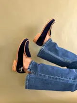 Mocasines de terciopelo azul marino con suela de madera y detalle de caballo bordado en dorado.