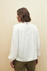 Camisa verde claro de viscosa suave, con cuello mao y botonadura parcial al frente. El detalle de frunces en los hombros y los puños abotonados le suman delicadeza y estilo.