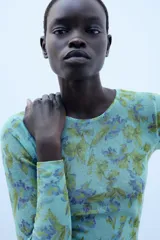 Jersey de punto Zara con cuello redondo y manga larga, con estampado floral a contraste en tonos verdes y morados sobre base celeste.