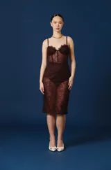 Vestido midi de encaje color marrón chocolate, con diseño tipo corset en el torso y breteles finos. Presenta transparencias en la falda y detalles de encaje en el escote.