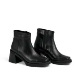 Bota corta de cuero negro con plataforma y taco cuadrado. Presenta un diseño de textura acanalada en la parte posterior del talón y cierre lateral.