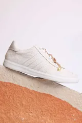 Zapatillas bajas color marrón con cordones y charms dorados.