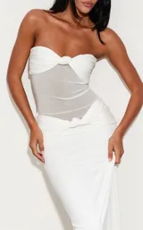 Vestido largo blanco de corte sirena con diseño strapless, cuerpo drapeado con nudo central y sección semitransparente en el torso.