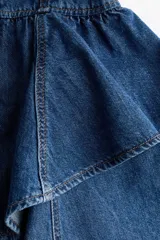 Vestido corto de denim azul con tirantes anchos, escote cuadrado, cuerpo entallado con costuras visibles y falda acampanada con doble volado en la cintura.
