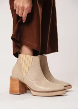 Botín de cuero color beige con textura reptil, elástico lateral y cierre interno. Tiene plataforma delantera y taco de madera.