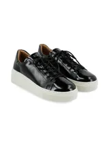 Sneaker Adelaida de suela elevada, confeccionado en cuero charol negro con cordones de algodón al tono y suela chunky de goma blanca.