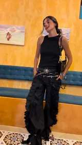 Pantalón largo negro de lino con apliques de tablas cosidas que generan textura y movimiento. Presenta tajos laterales y bolsillos delanteros y traseros.