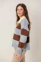 Buzo de tejido de punto con diseño de rayas horizontales anchas en color gris y marrón. Presenta cuello polo en tono crema con cierre frontal de dos botones y mangas largas con puños acanalados.