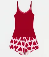 Conjunto de pijama short doll de algodón, compuesto por un top rojo con tirantes finos y encaje en el escote, y un short blanco con estampado de corazones rojos.