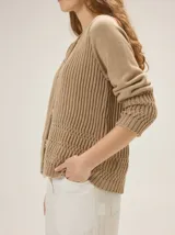 Cardigan de punto color blanco marfil, con escote en V, mangas largas con detalles de tejido calado y cierre frontal de botones con efecto madera.