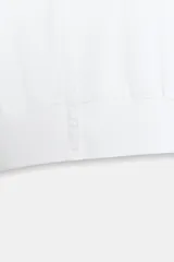Top de algodón blanco de manga larga, con escote en V y cierre frontal con botones. Presenta bajo y puños en rib elástico.