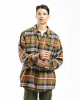 Sobrecamisa de franela con diseño de cuadros en tonos mostaza, verde, blanco y rojo. Presenta cuello clásico, cierre frontal con botones, dos bolsillos frontales con tapa y botón, y puños abotonados.