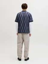 Camiseta tipo polo de manga corta con diseño de rayas verticales en tonos gris y negro. Presenta cuello polo negro, escudo deportivo en el pecho y estampa frontal con texto en color blanco. Confeccionada en tejido técnico de poliéster con corte holgado.