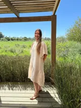 Vestido largo color beige, de corte amplio, con mangas cortas abullonadas y volado en el ruedo.