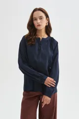 Blusa azul marino de viscosa, con cuello mao, escote con botones y frunces. Presenta mangas largas holgadas y detalles bordados al tono en el frente.