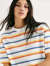 Camiseta de manga corta con cuello redondo, color blanco, con un patrón de rayas horizontales en tonos cálidos y azules (naranja, amarillo, rojo, azul oscuro y celeste).