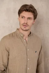 Camisa de lino color beige con cuello mao, corte slim fit y mangas 3/4 con botón para sujetar.