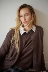 Cardigan azul de punto fino, con cuello redondo y cierre frontal de botones negros.