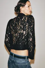 Blazer de encaje negro con hilatura de algodón, cuello redondo, manga larga y cierre frontal de botones.