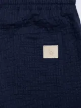 Pantalón azul marino de algodón con textura, cintura elastizada con cordón, bolsillos laterales y trasero.