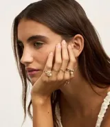 Set de seis anillos dorados con diferentes diseños: uno con una moneda, otro con eslabones, uno liso, otro con perlas y otro con forma de caracol.