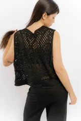 Chaleco negro de tejido de punto abierto, sin mangas y sin cierre, con cuello solapa.