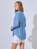 Camisa celeste con rayas verticales blancas, de corte clásico, cuello a la base, escote en V y cierre frontal con botones.