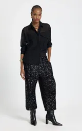 Pantalon de corte recto y holgado, confeccionado en tejido cubierto de lentejuelas negras. Presenta una cinturilla elástica ancha en contraste, bolsillos laterales con cierre y diseño de tiro alto.