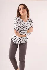 Pijama de dos piezas, compuesto por una remera de manga larga blanca con lunares negros y un pantalón largo gris.