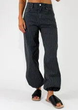 Pantalon de denim azul con diseño de rayas verticales blancas, de corte holgado y estilo relajado.